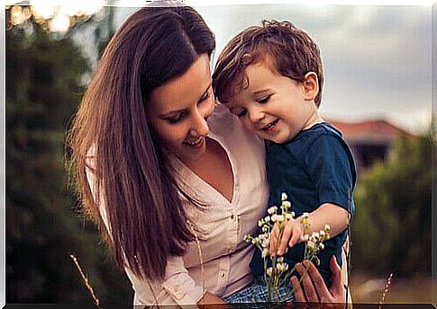 Super mom-holding-her-son-in-arms-while-seeing-a-flower