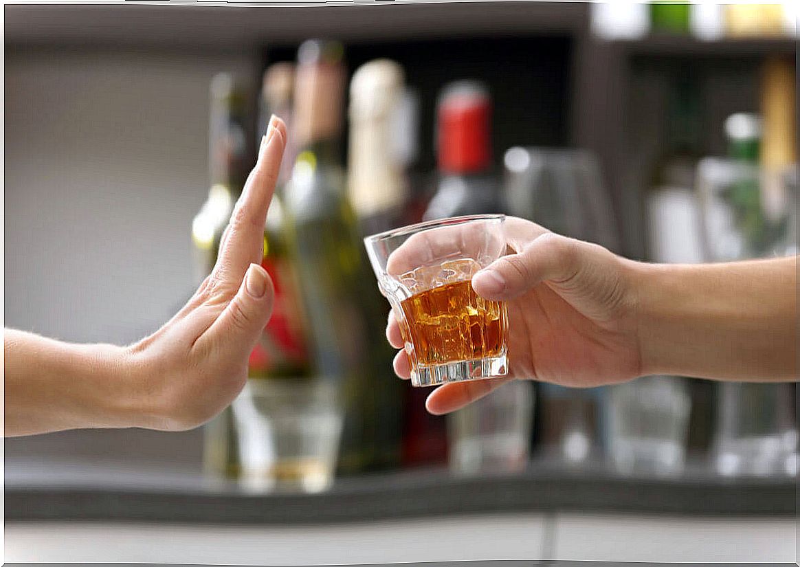 Hand rejects glass with alcohol.