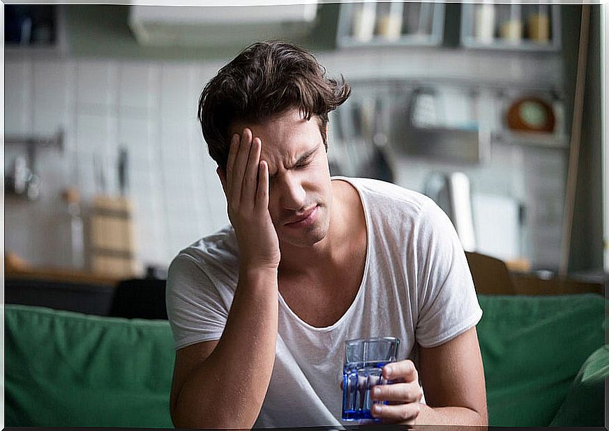 Man sitting on sofa with headache.