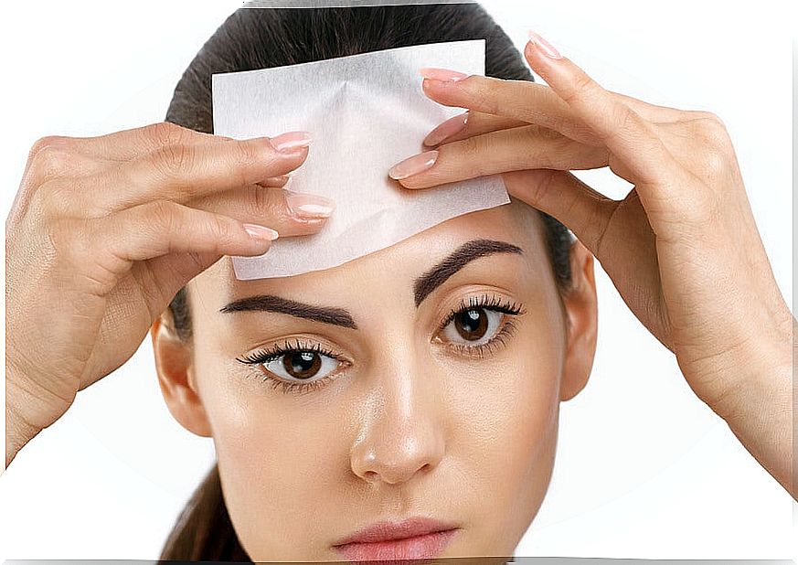 Woman applying absorbent paper to her face.