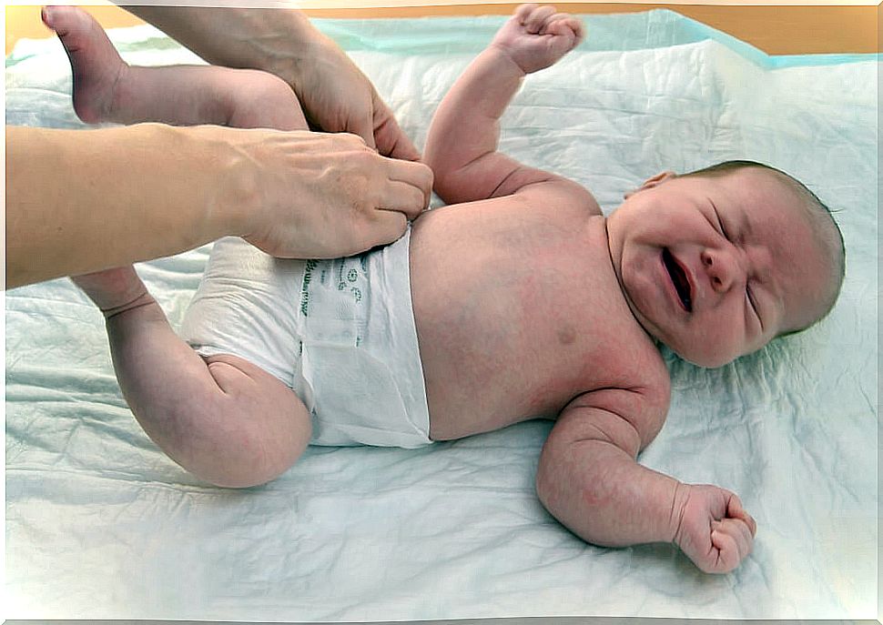 Baby crying while his mother learns to lower the skin of the penis.